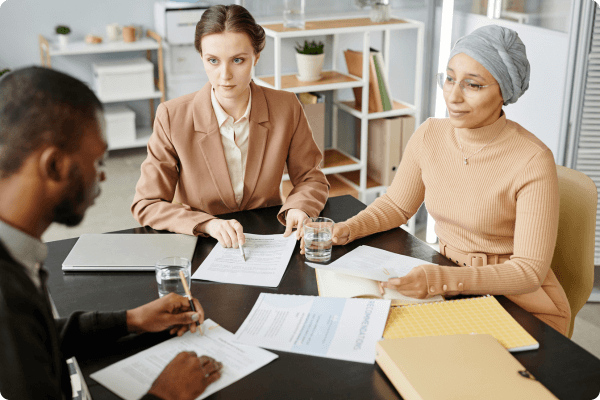 Three HR workers sitting together at a desk discussing business. (1)